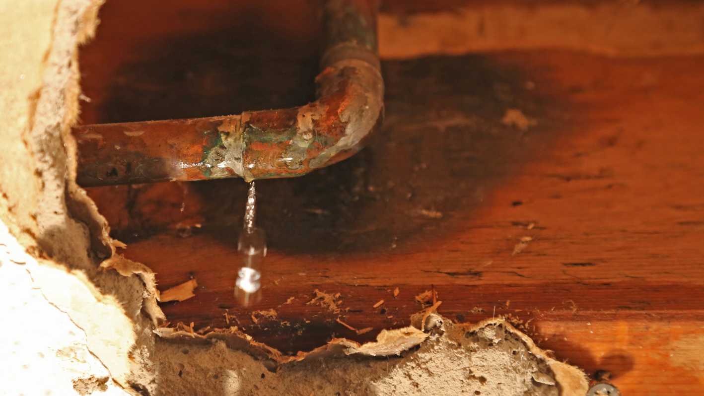 A rusted pipe sticking out of the side of a building